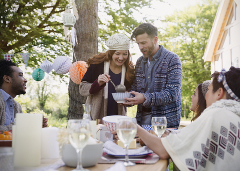 Ehepaar serviert Freunden am Terrassentisch das Mittagessen, lizenzfreies Stockfoto