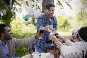 Freunde stoßen mit Weingläsern am Gartenparty-Tisch an - CAIF16065