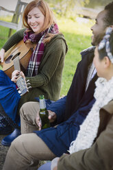 Frau spielt Gitarre mit Freunden, die Bier trinken - CAIF16066