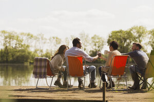 Freunde stoßen mit Kaffeebechern am sonnigen Steg am See an - CAIF16076