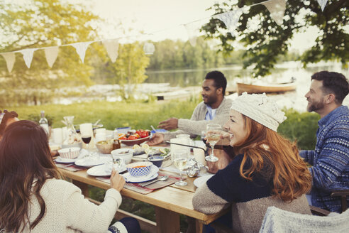 Freunde genießen das Mittagessen am Tisch auf der Seeterrasse - CAIF16083