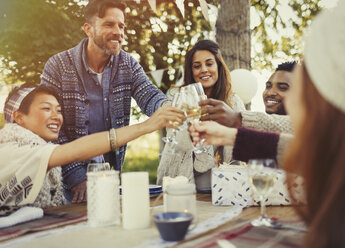 Friends toasting champagne glasses at birthday party patio table - CAIF16084