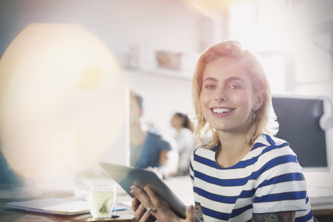 Portrait lächelnde junge kreative Geschäftsfrau mit digitalem Tablet im Büro, lizenzfreies Stockfoto