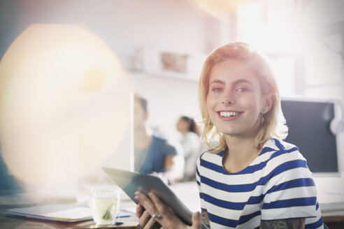 Portrait lächelnde junge kreative Geschäftsfrau mit digitalem Tablet im Büro - CAIF16105