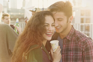 Laughing young couple hugging at rooftop party - CAIF16113