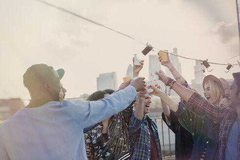 Begeisterte junge Erwachsene stoßen bei einer Dachterrassenparty mit Cocktails an - CAIF16116
