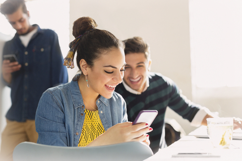 Smiling young business people texting with cell phone stock photo