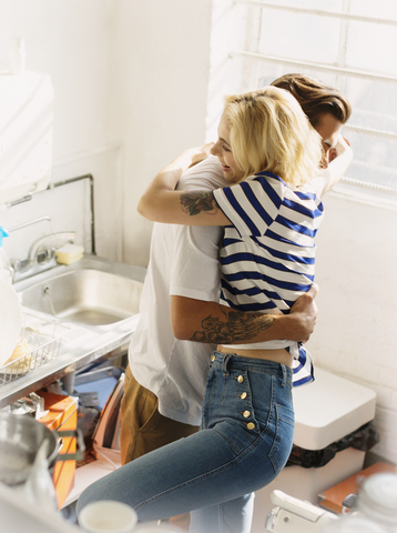 Junges Paar, das sich in der Wohnküche umarmt, lizenzfreies Stockfoto