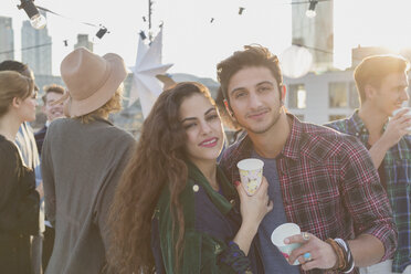 Portrait smiling young couple drinking at rooftop party - CAIF16143