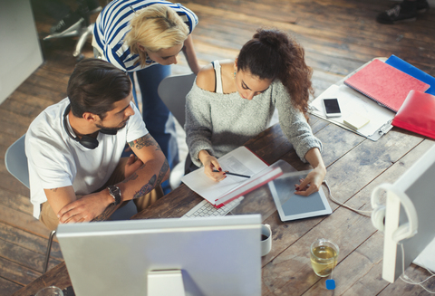 Kreative junge Geschäftsleute, die im Büro Papierkram besprechen, lizenzfreies Stockfoto