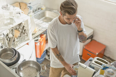 Mann benutzt Espressomaschine und telefoniert in der Wohnküche - CAIF16149