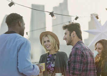 Young adult friends talking and drinking at rooftop party - CAIF16150