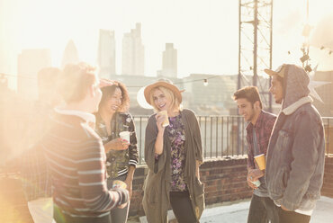 Young adult friends talking and drinking at rooftop party - CAIF16154