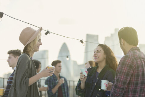 Young adult friends drinking and talking at rooftop party - CAIF16156