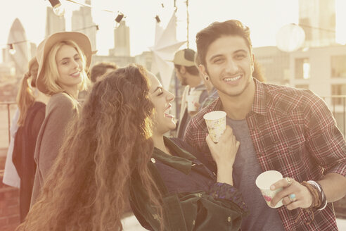 Young adult friends drinking and laughing at rooftop party - CAIF16158