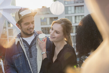 Young couple drinking and enjoying rooftop party - CAIF16161