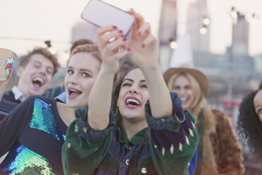 Junge Frauen lachen und machen ein Selfie auf einer Dachterrassenparty - CAIF16168