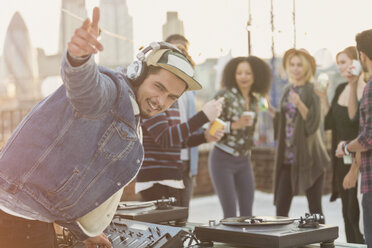 Porträt eines begeisterten DJs, der auf einer Dachterrassenparty gestikuliert - CAIF16176