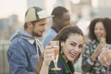 Porträt einer begeisterten jungen Frau, die auf einer Party Champagner trinkt - CAIF16181