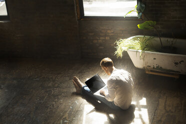 High angle view of man using laptop computer while sitting on floor at home - CAVF07920