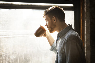 Mann schaut beim Kaffeetrinken weg - CAVF07935