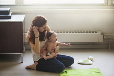 Mutter sitzt mit Tochter zu Hause - CAVF07988