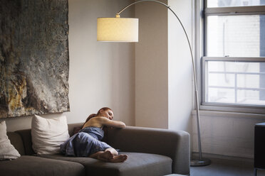 Woman relaxing on sofa at home - CAVF08021