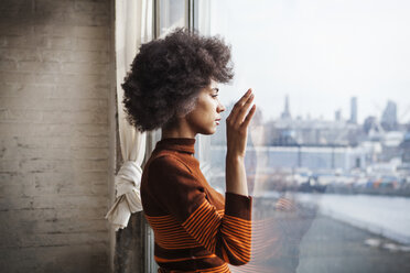 Side view of woman looking though window at home - CAVF08046