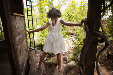 Rückansicht eines auf Baumstämmen stehenden Mädchens, lizenzfreies Stockfoto
