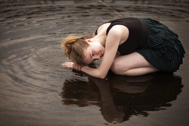 Seitenansicht einer im flachen Wasser knienden Frau am Strand - CAVF08131