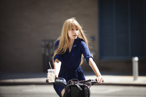 Frau schaut beim Radfahren auf der Straße in der Stadt weg - CAVF08138