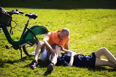 Cheerful couple relaxing on grassy field - CAVF08147