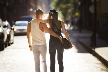 Rückansicht eines Paares, das sich umarmt, auf einer Straße in der Stadt - CAVF08150
