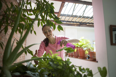 Schwangere Frau besprüht Pflanzen zu Hause mit Wasser - CAVF08173