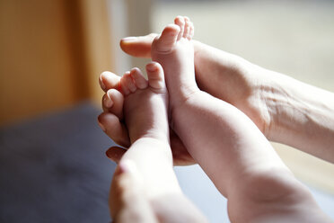 Ausgeschnittenes Bild einer Mutter, die die Füße eines kleinen Mädchens zu Hause hält - CAVF08216