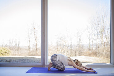 Seitenansicht einer Frau, die zu Hause Yoga in der nach unten gerichteten Hundestellung praktiziert - CAVF08238