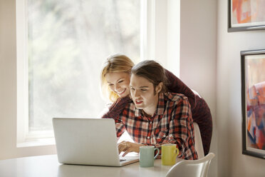 Happy couple using laptop together at home - CAVF08272