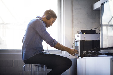 Side view of man listening music at home - CAVF08279