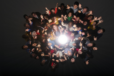 Vielfältige Menschenmenge jubelt um helles Licht herum, lizenzfreies Stockfoto