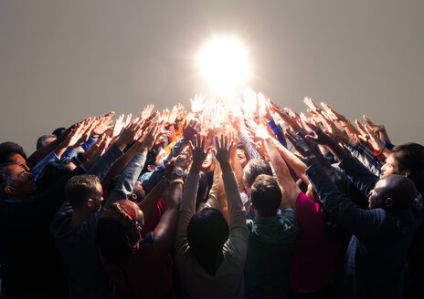 Diverse crowd reaching for bright light - CAIF16214