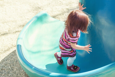 Baby girl climbing slide at playground - CAIF16225