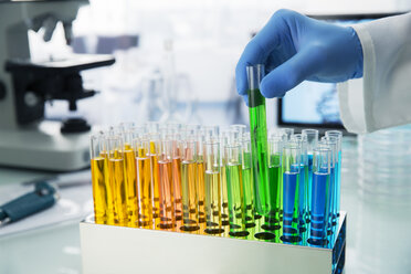 Wissenschaftlerin nimmt Reagenzglas aus dem Regal auf dem Tresen im Labor - CAIF16230