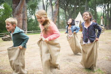 Children having sack race in field - CAIF16232
