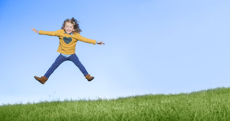 Girl jumping for joy on grassy hill - CAIF16239