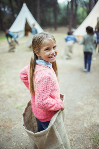 Mädchen lächelnd im Sack auf dem Campingplatz, lizenzfreies Stockfoto