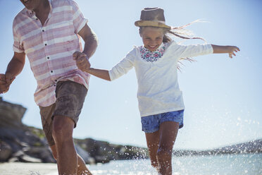 Family running in water on beach - CAIF16276