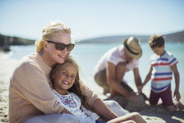 Grandmother hugging granddaughter on beach - CAIF16279