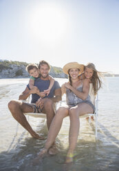 Family sitting in chairs in waves - CAIF16282