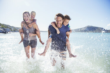 Family running in water on beach - CAIF16290