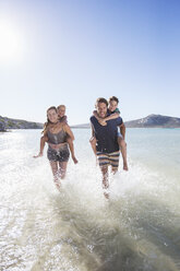 Familie läuft im Wasser am Strand - CAIF16293